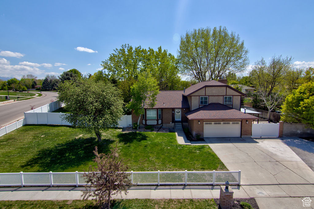 Tri-level home with an attached garage, concrete driveway, fence private yard, and a front lawn
