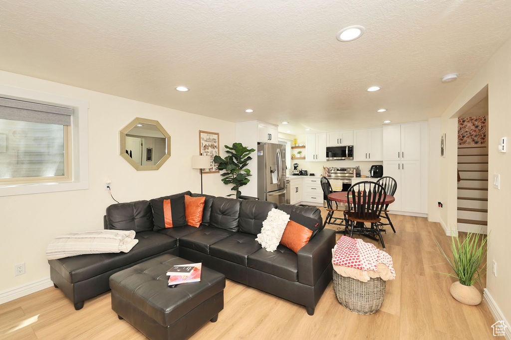 Living room with light wood-type flooring, recessed lighting, baseboards, and stairs