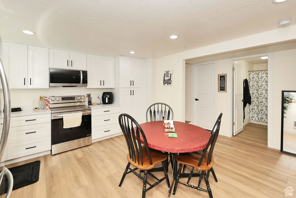Dining area featuring recessed lighting, baseboards, light wood finished floors, and a textured ceiling