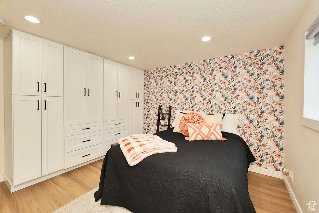 Bedroom with baseboards, wallpapered walls, a closet, light wood finished floors, and recessed lighting