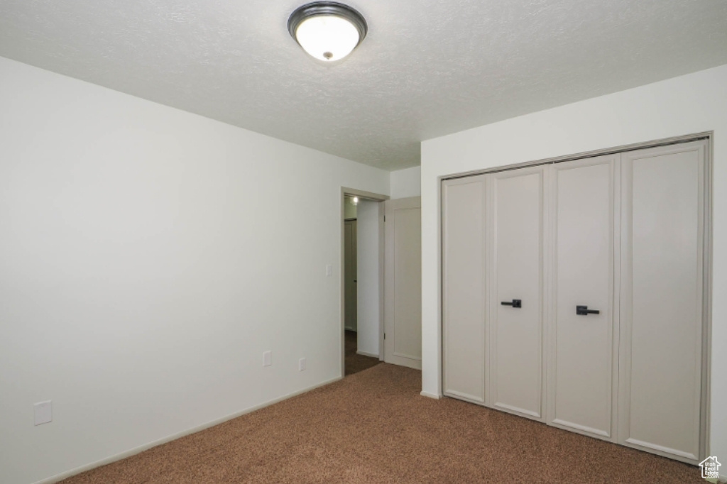 Unfurnished bedroom with carpet floors, a textured ceiling, and a closet