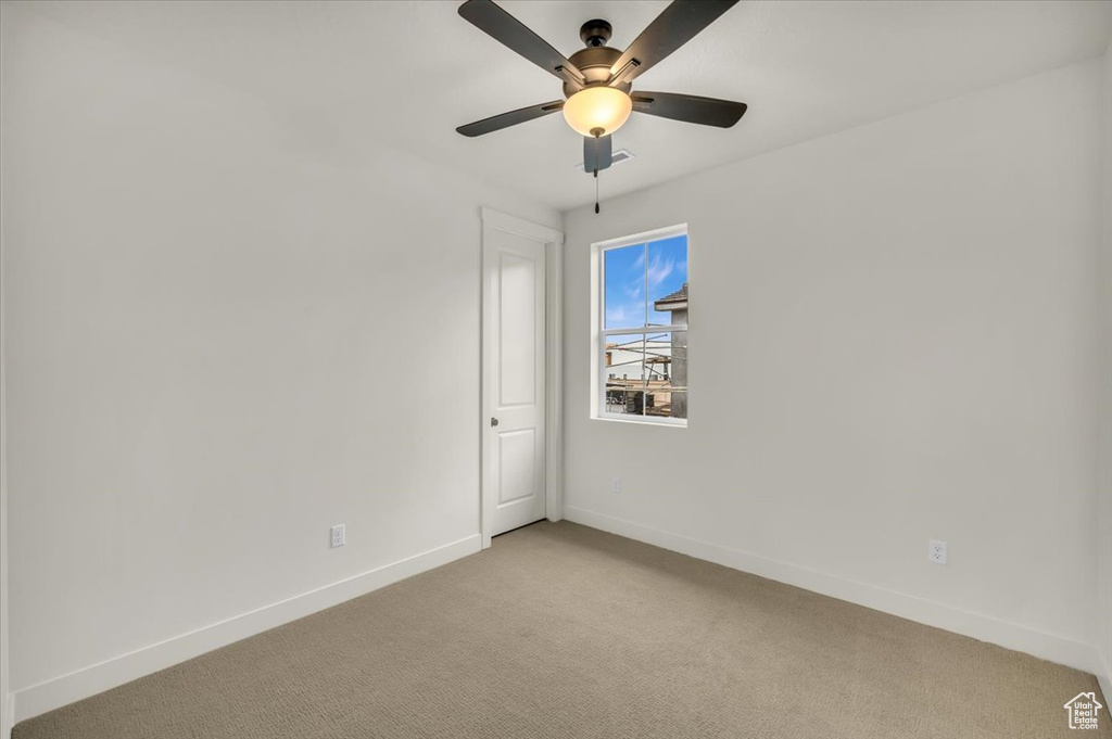 Unfurnished room with a ceiling fan, baseboards, and light carpet