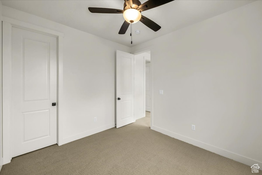 Unfurnished bedroom with baseboards, a ceiling fan, and light colored carpet