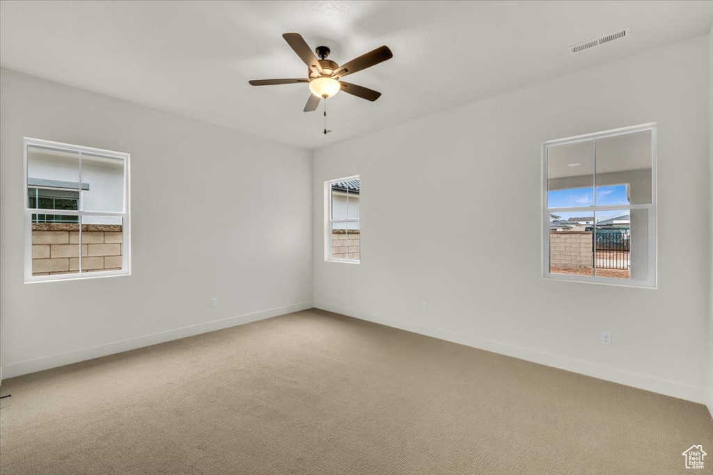 Unfurnished room featuring visible vents, plenty of natural light, and carpet