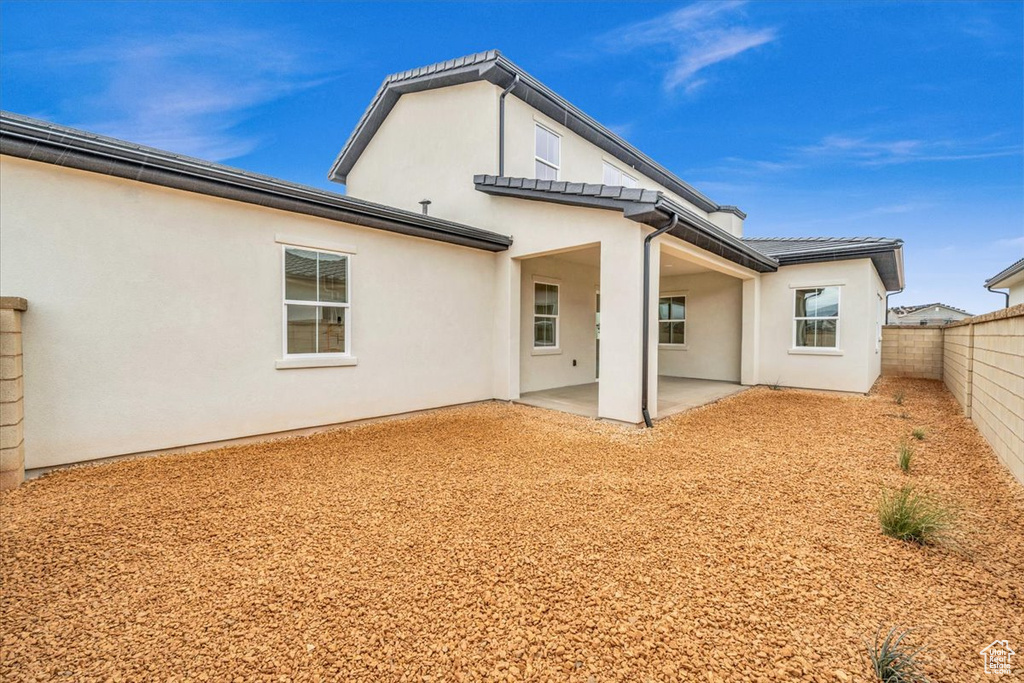 Back of property with a fenced backyard, a patio, and stucco siding