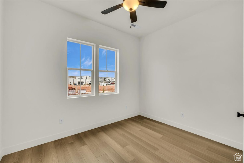 Empty room featuring baseboards, ceiling fan, and light wood-type flooring