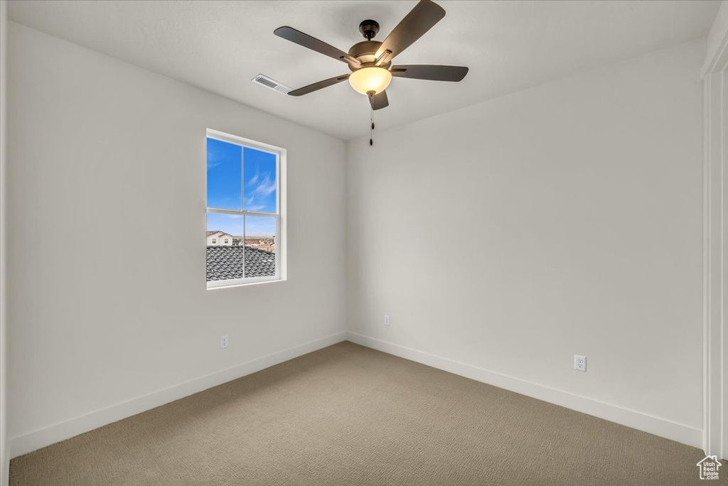 Carpeted spare room with a ceiling fan, baseboards, and visible vents