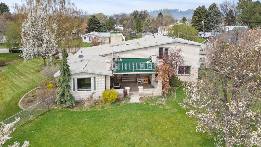 Rear view of property featuring a lawn, brick siding, a wooden deck, and a patio area