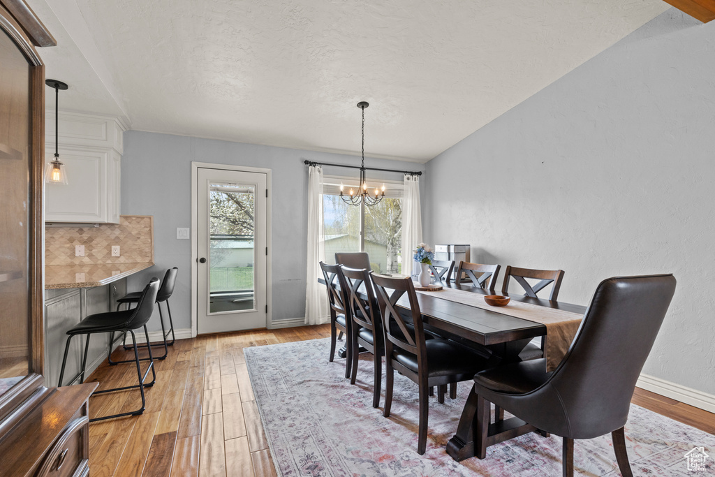 Dining space featuring an inviting chandelier, a textured ceiling, baseboards, and light wood-type flooring
