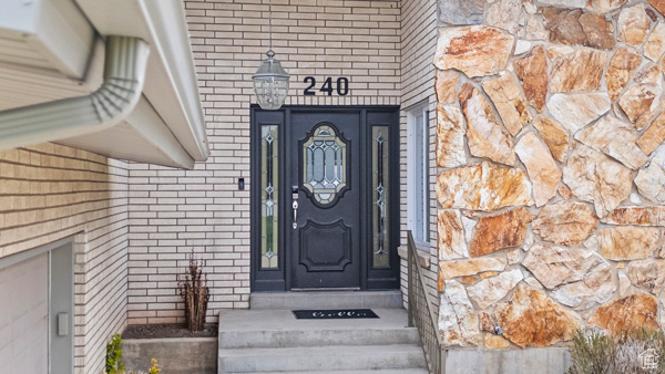 View of exterior entry featuring brick siding and stone siding