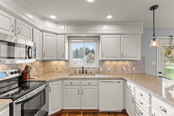 Kitchen featuring a sink, light countertops, stainless steel appliances, and white cabinetry