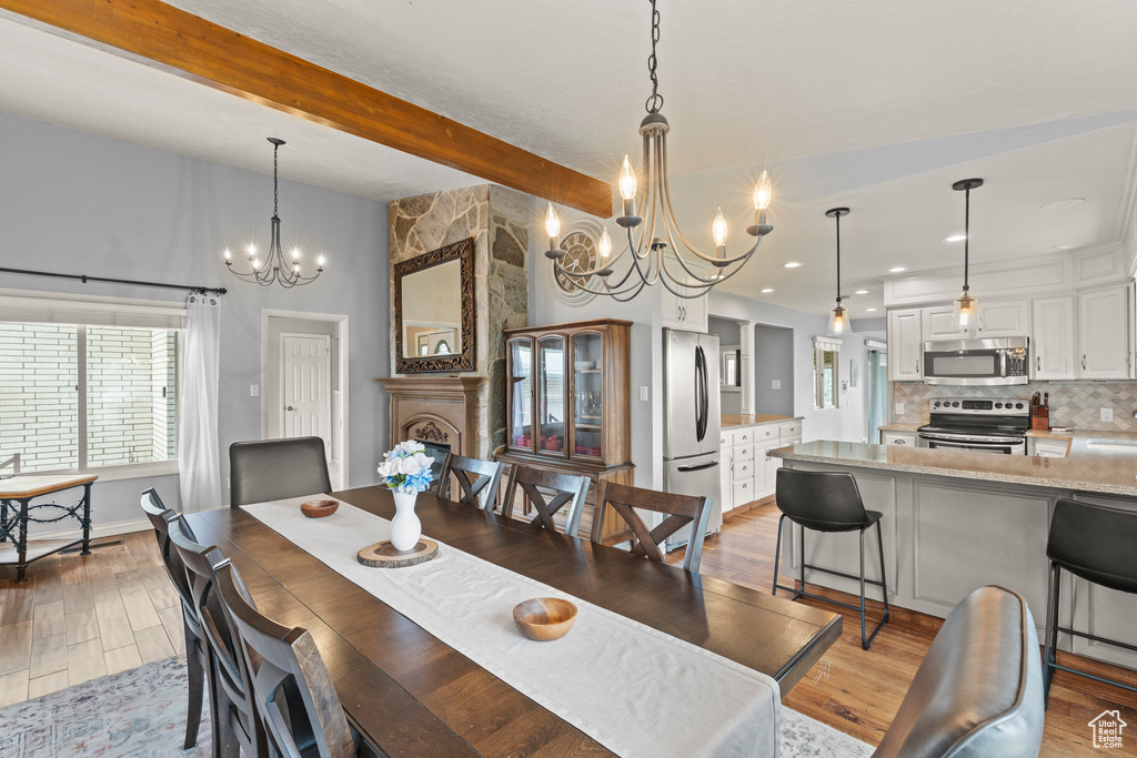 Dining room with recessed lighting, an inviting chandelier, beam ceiling, and light wood-type flooring