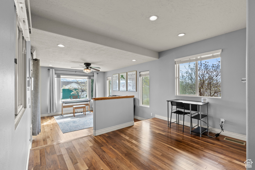 Interior space with a textured ceiling, hardwood / wood-style floors, recessed lighting, baseboards, and visible vents