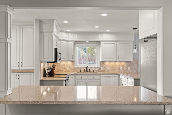 Kitchen with a sink, white cabinetry, appliances with stainless steel finishes, and tasteful backsplash