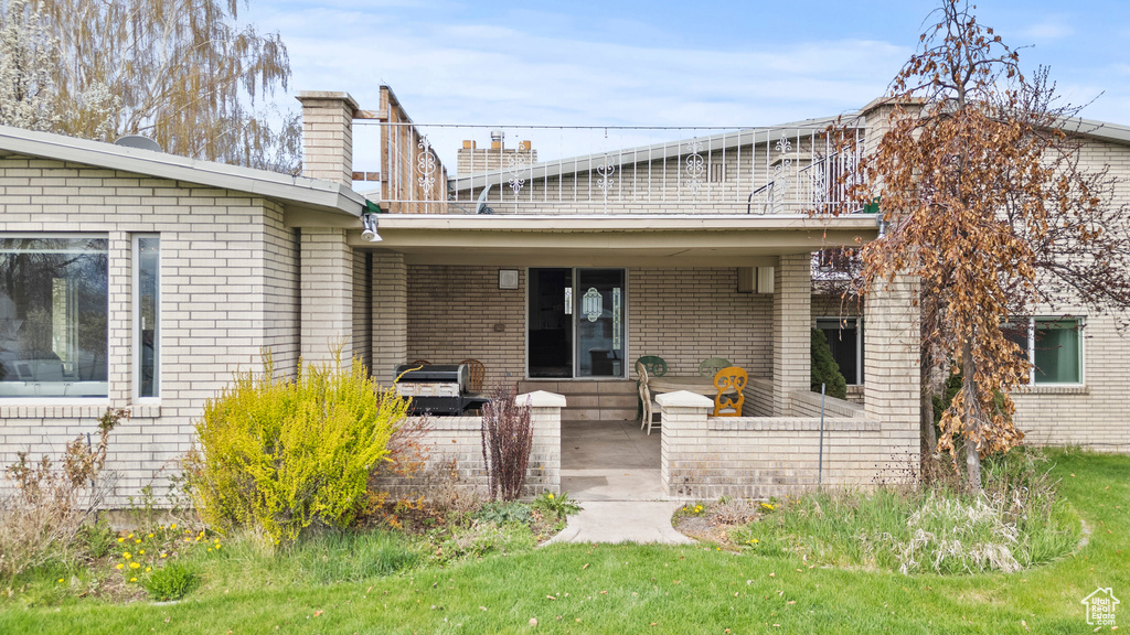 Back of property with brick siding, a lawn, a chimney, and a patio
