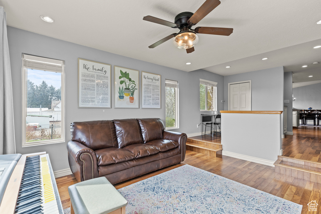 Living room featuring baseboards, a ceiling fan, wood finished floors, and recessed lighting