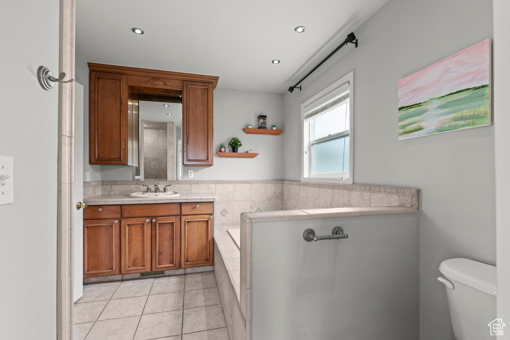 Full bath featuring tiled bath, vanity, toilet, tile patterned floors, and recessed lighting
