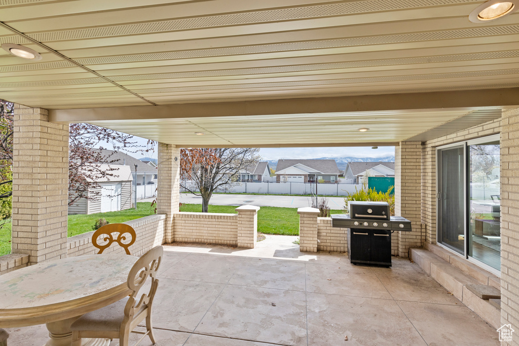 View of patio with an outbuilding, a residential view, fence, outdoor dining space, and a grill