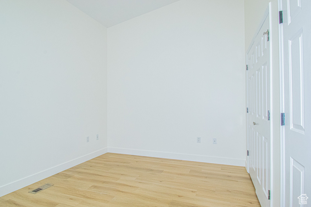 Empty room with baseboards, visible vents, and light wood finished floors