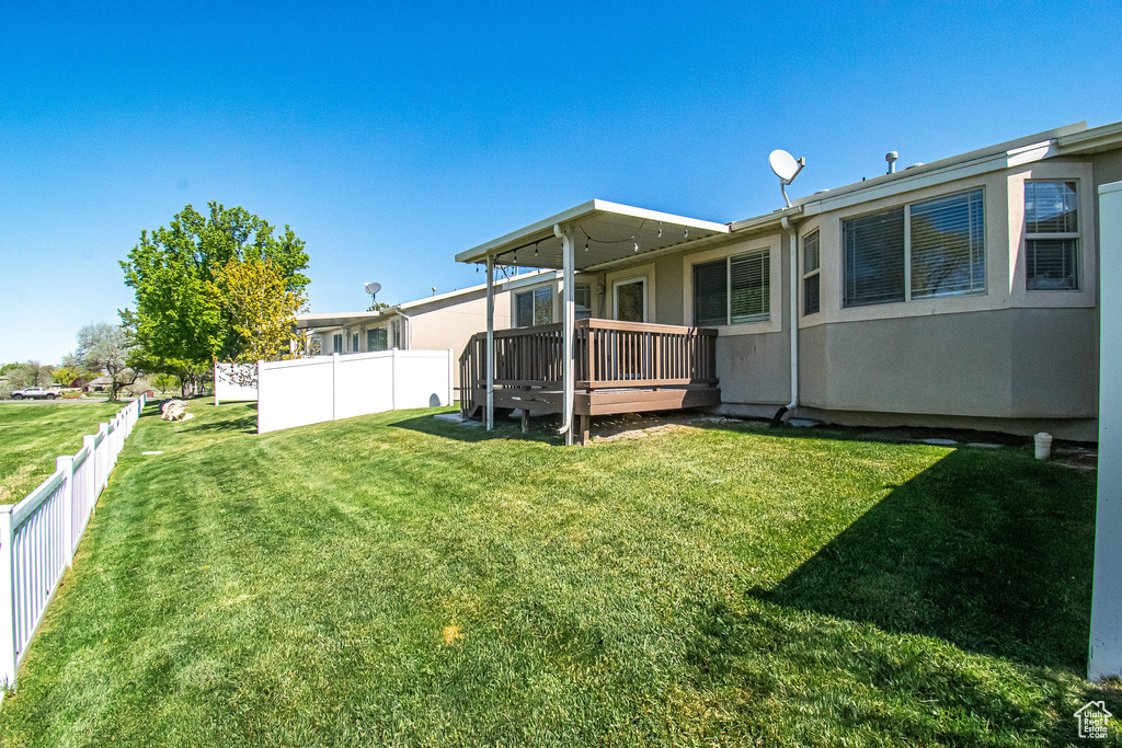 Back of property with a yard, fence, and a wooden deck