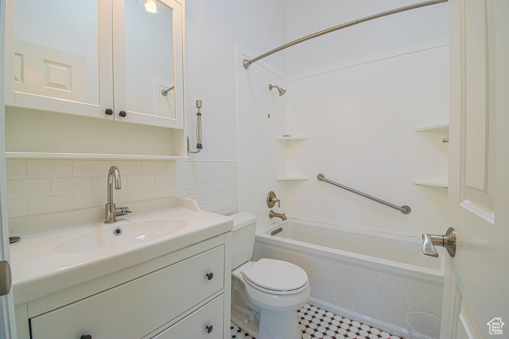 Bathroom featuring backsplash, toilet, bathtub / shower combination, and vanity