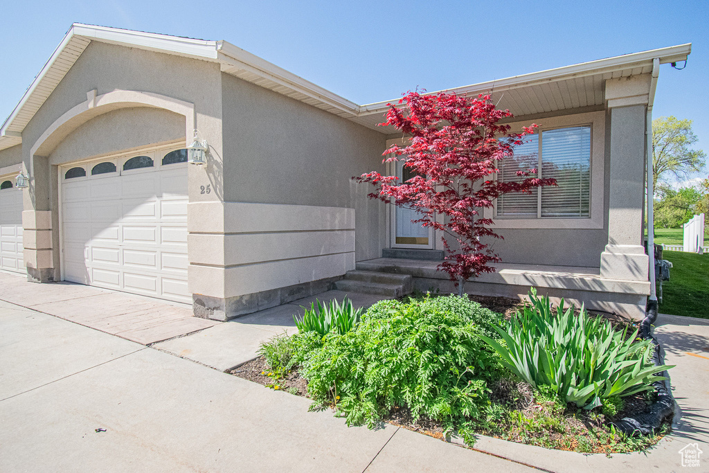 View of front of property with entry steps, an attached garage, driveway, and stucco siding
