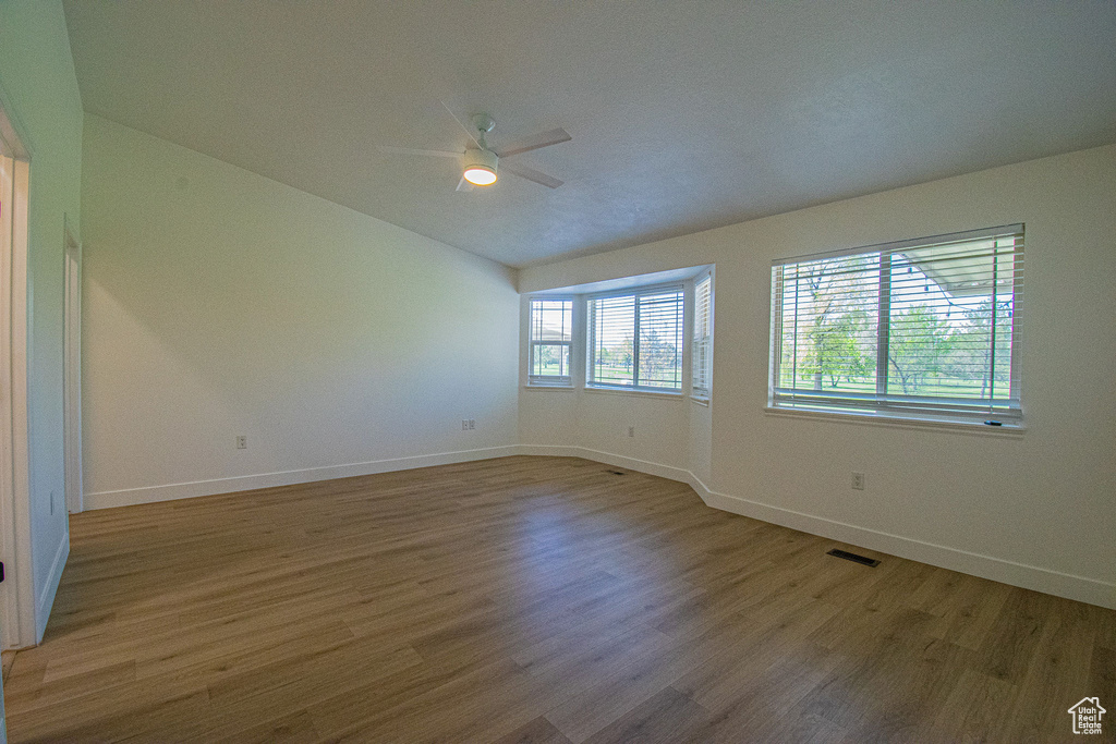 Empty room with baseboards, ceiling fan, wood finished floors, and visible vents