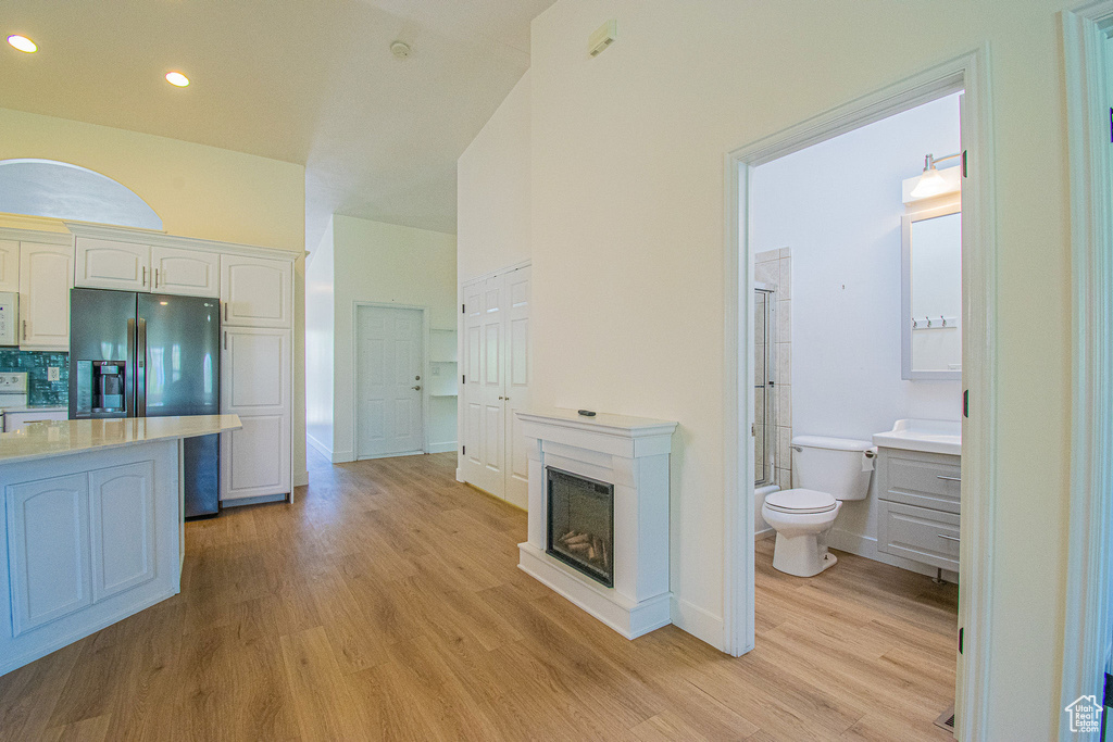 Kitchen featuring white cabinets, light countertops, light wood-style flooring, baseboards, and fridge with ice dispenser