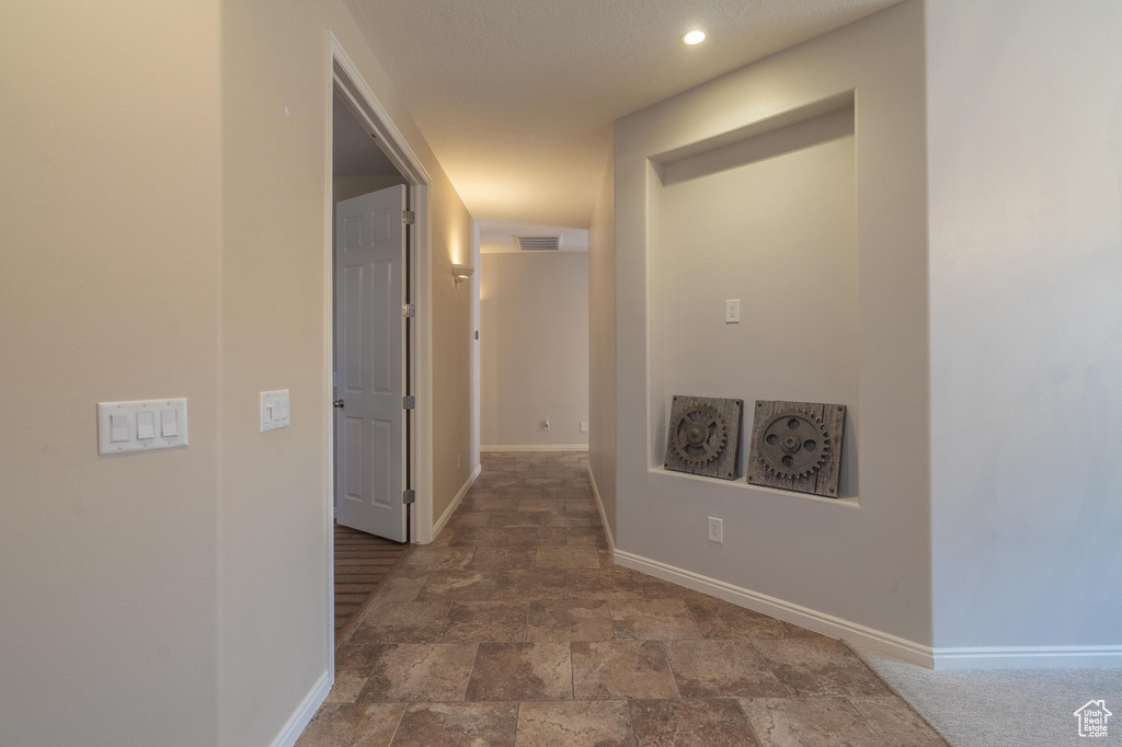 Hall featuring stone finish flooring, baseboards, visible vents, and recessed lighting