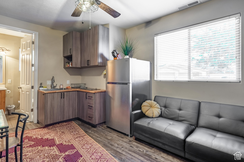 Kitchen featuring visible vents, freestanding refrigerator, a ceiling fan, wood finished floors, and a sink