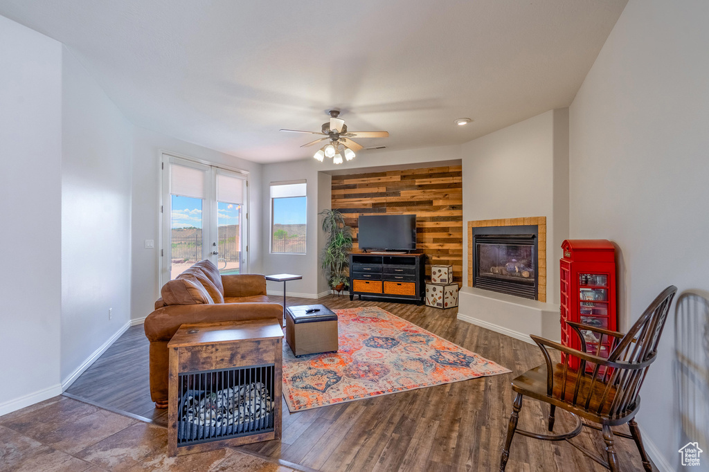 Living area featuring a tiled fireplace, baseboards, ceiling fan, and wood finished floors