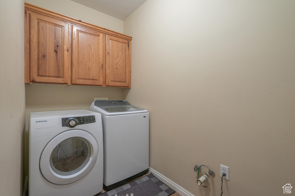 Laundry room featuring baseboards, cabinet space, and washing machine and dryer