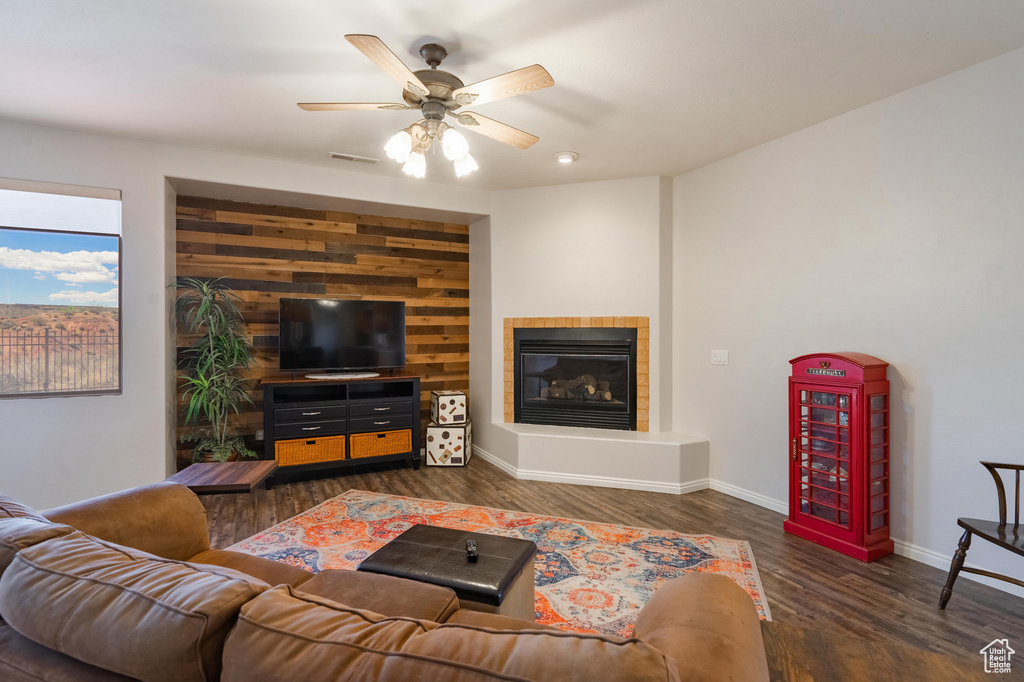 Living area with ceiling fan, visible vents, wood finished floors, a tile fireplace, and baseboards