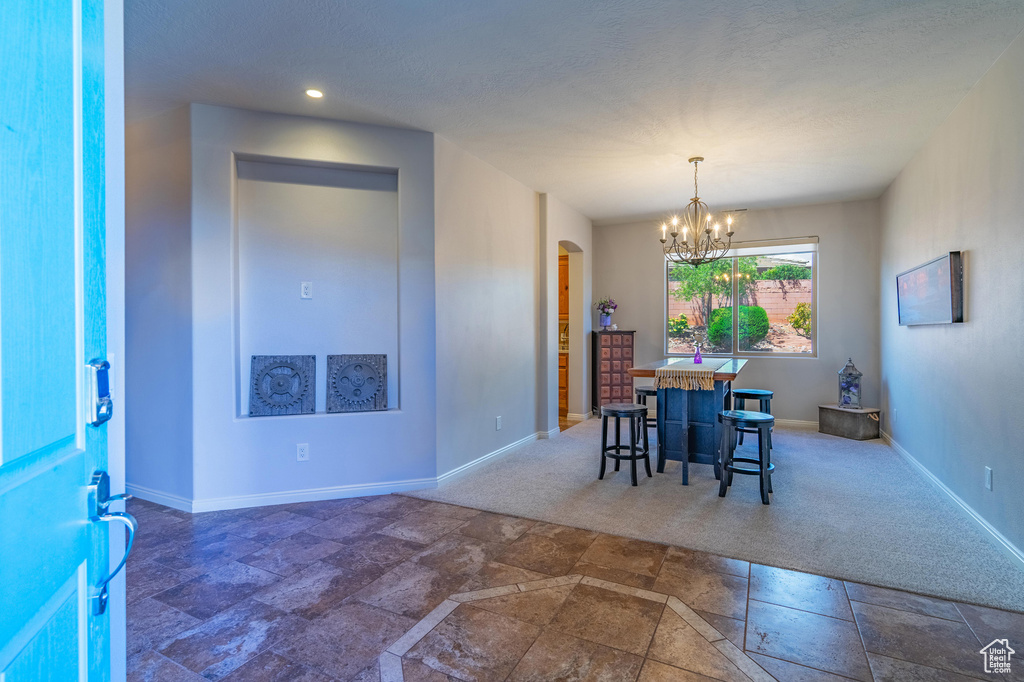 Dining room featuring stone finish flooring, arched walkways, baseboards, an inviting chandelier, and recessed lighting