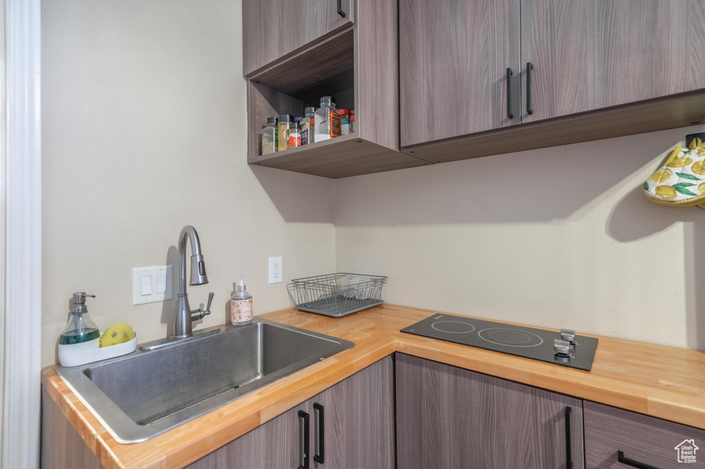 Kitchen with a sink, black electric cooktop, and butcher block counters