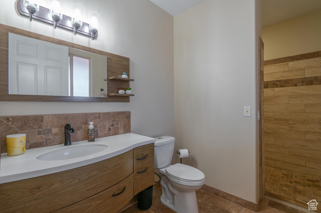 Full bath featuring vanity, backsplash, toilet, and tiled shower