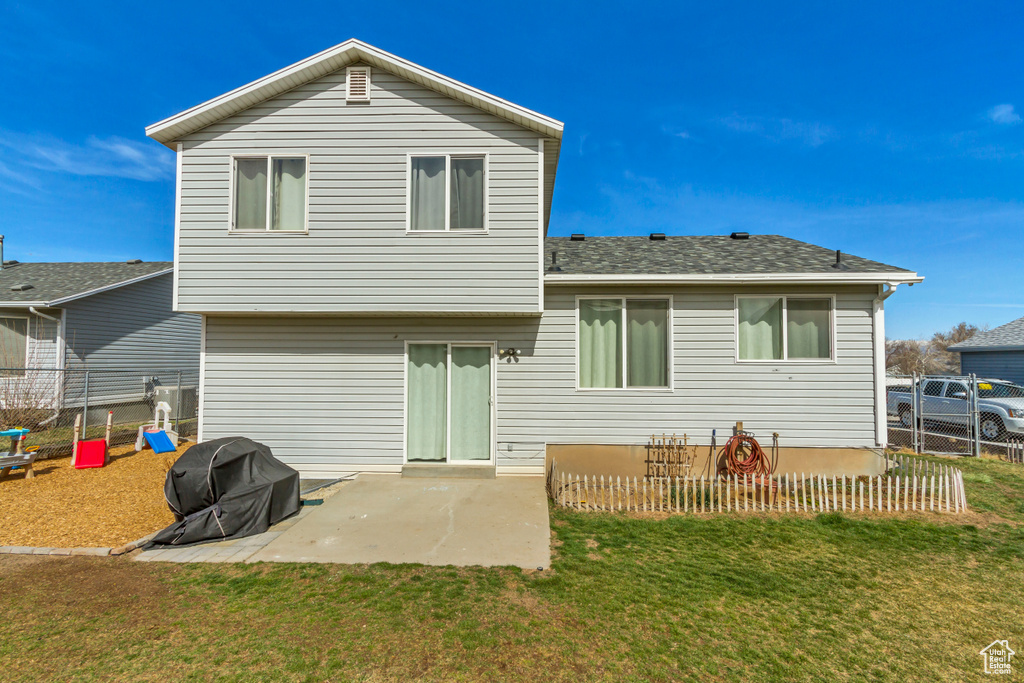Rear view of property with a yard, fence, and a patio area