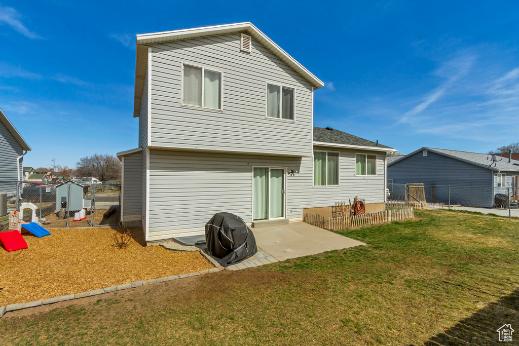 Back of property featuring a gate, a lawn, a patio, and fence
