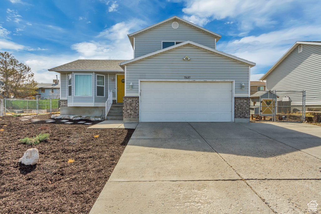 View of front of property featuring concrete driveway, a gate, brick siding, and an attached garage