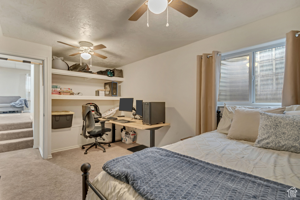 Carpeted bedroom featuring ceiling fan and a textured ceiling