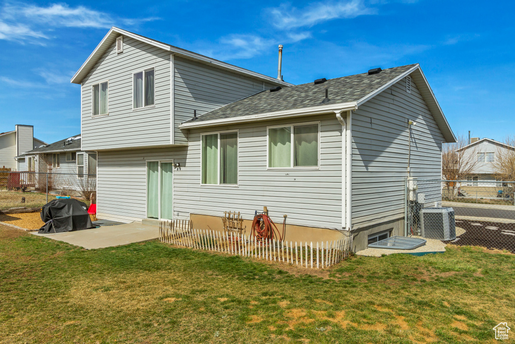 Back of house with a patio, cooling unit, a lawn, and fence