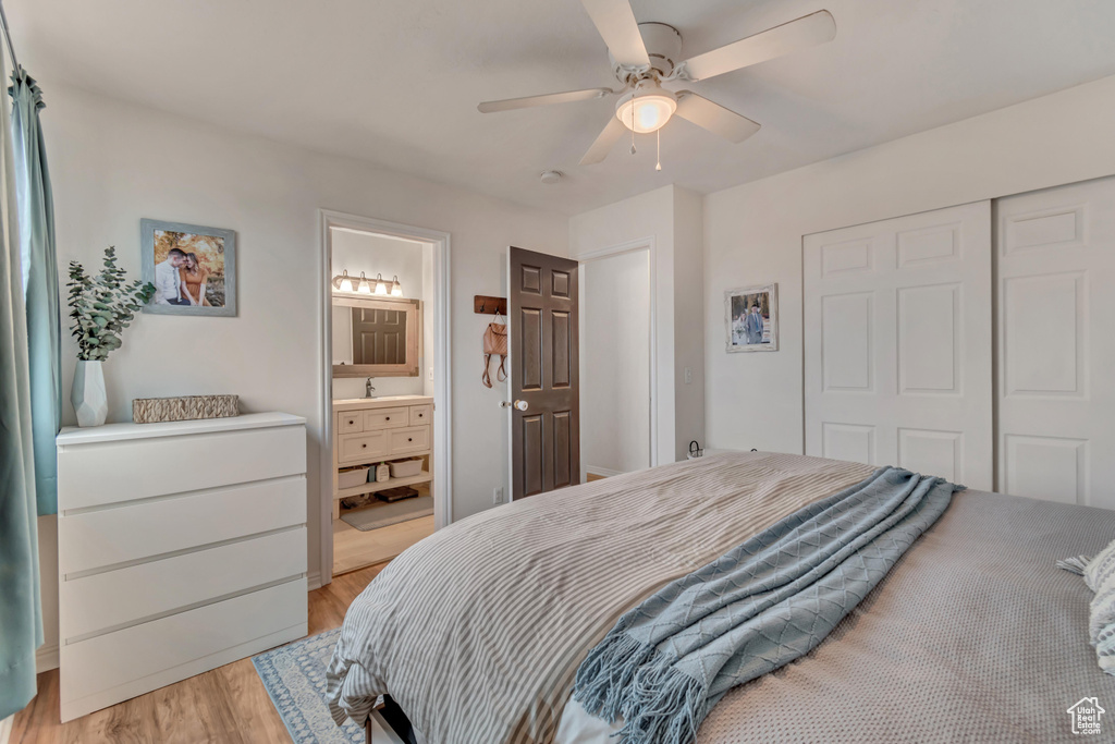 Bedroom featuring light wood-type flooring, sink, ceiling fan, ensuite bath, and a closet