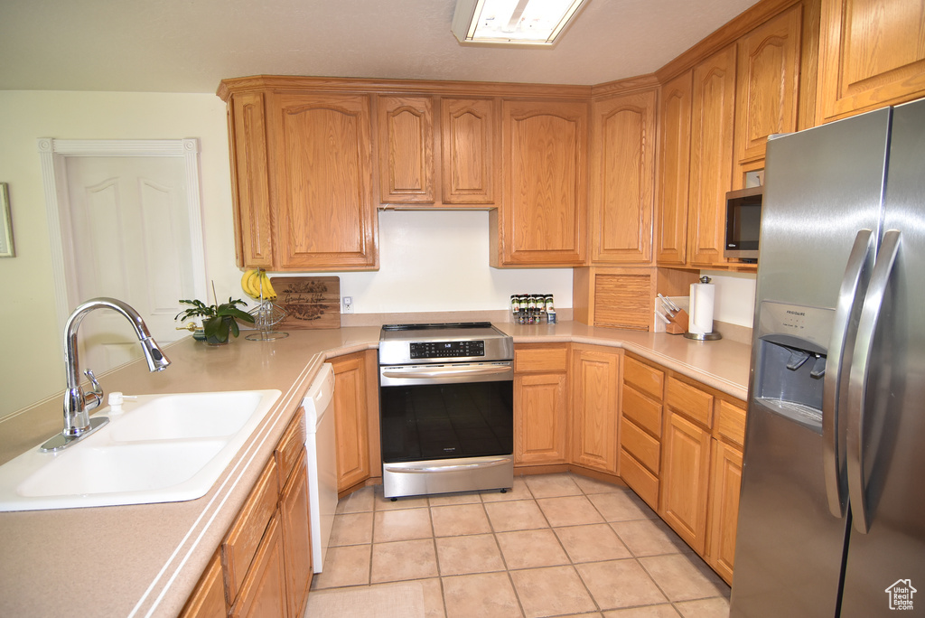 Kitchen featuring stainless steel appliances, a sink, light countertops, and light tile patterned flooring