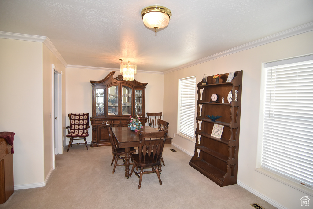 Dining space with light carpet, crown molding, a chandelier, and baseboards