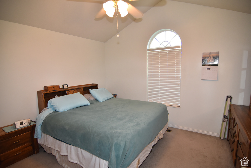 Bedroom featuring vaulted ceiling, light carpet, baseboards, and a ceiling fan