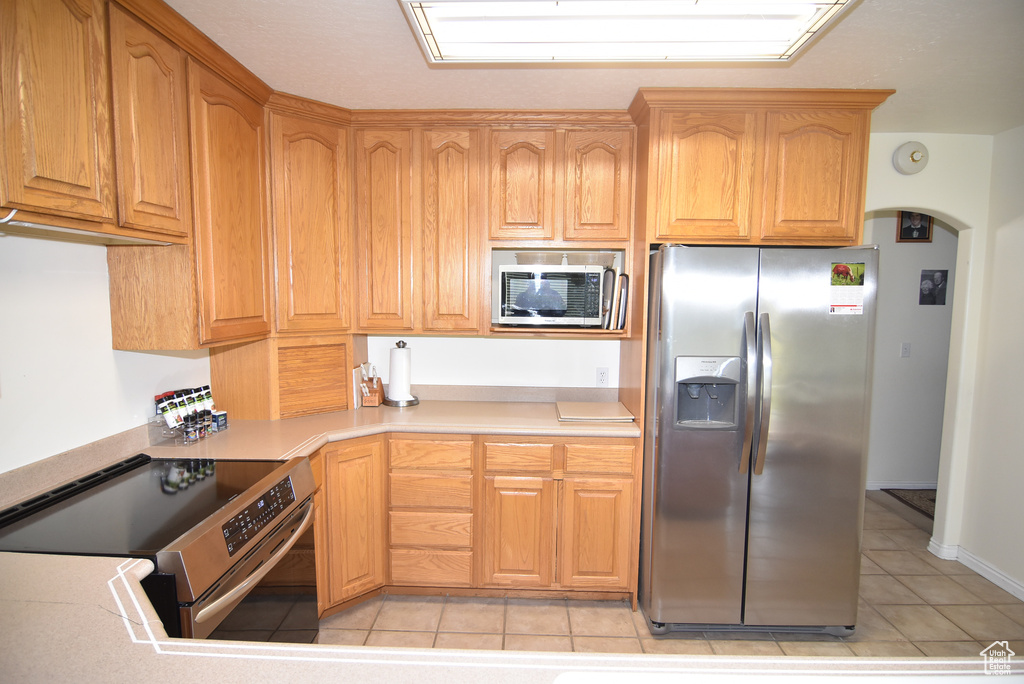 Kitchen featuring appliances with stainless steel finishes, light tile patterned floors, light countertops, and arched walkways