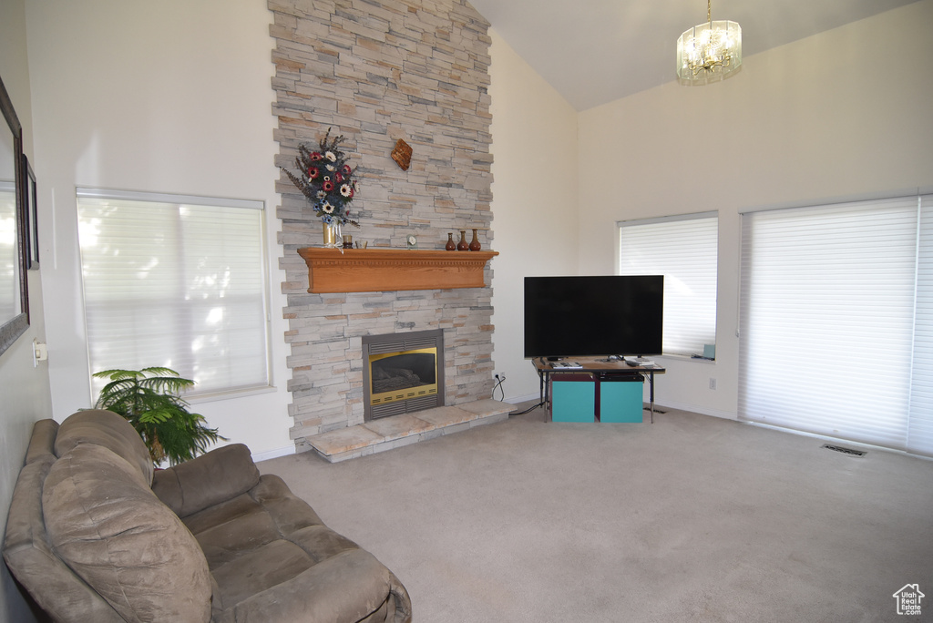 Carpeted living room with high vaulted ceiling, a fireplace, and a chandelier