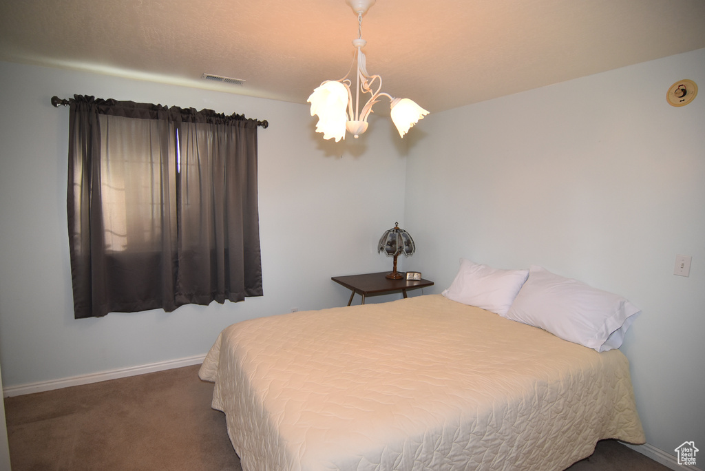Bedroom with a chandelier, carpet, and baseboards