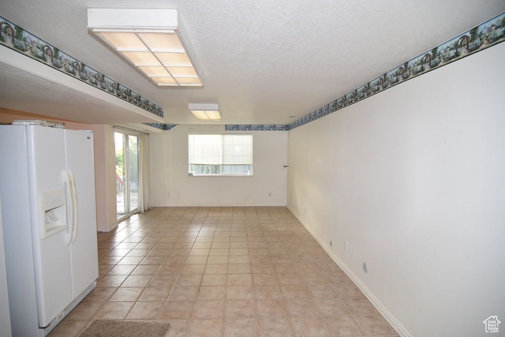 Empty room with a textured ceiling and light tile patterned floors