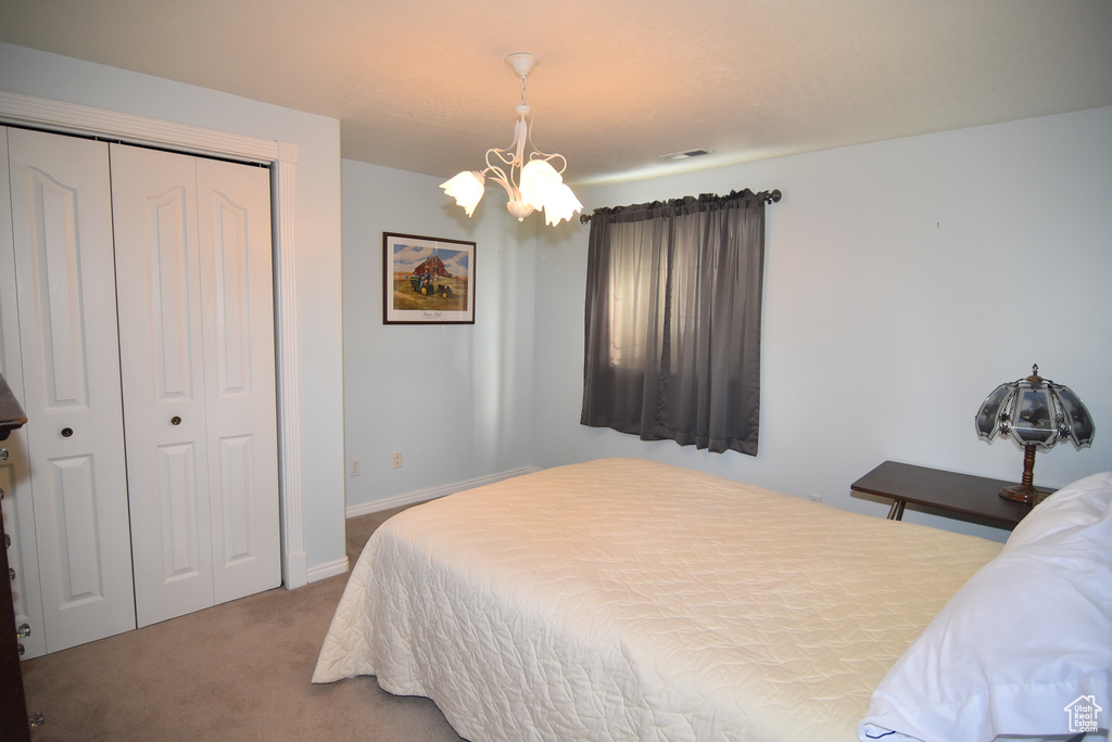 Bedroom with a chandelier, carpet floors, a closet, and baseboards